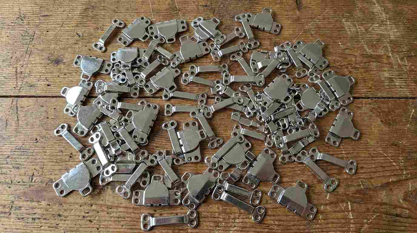pant hook types, Different pant hook types in silver metal are grouped together on a wooden surface.